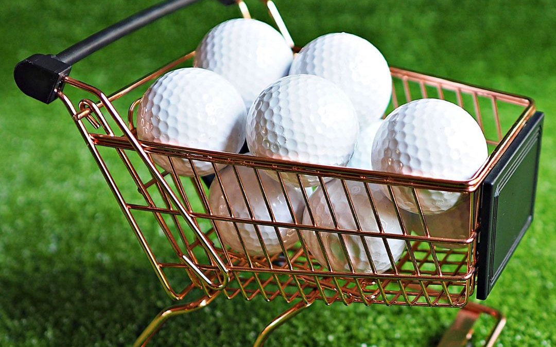 Un petit caddie rempli de balles de golf sur le gazon